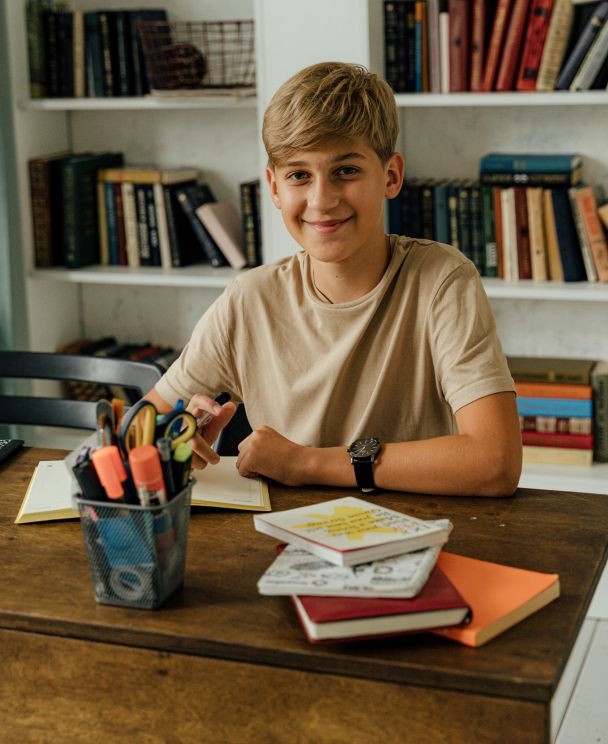 Boy at a desk smiling while doing English homework